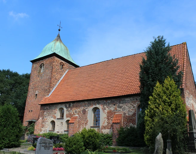 Kirche Bühren Historische Backsteinkirche mit markantem Turm und begrüntem Umfeld unter blauem Himmel.