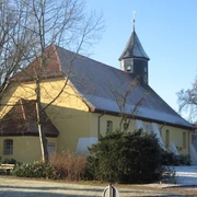 St. Jacobi-Kirche Husum Historische Kirche mit gelbem Anstrich und markantem Holzturm, umgeben von Bäumen im Winter.