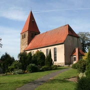 Willehadikirche in Eystrup Die Willehadikirche in Eystrup mit rotem Dach und Turm umgeben von einem gepflegten Garten.