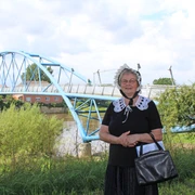 Gewandete Stadtführerin Nienburg Eine Frau in historischer Tracht steht vor einer blauen Brücke an einem Flussufer in Nienburg.