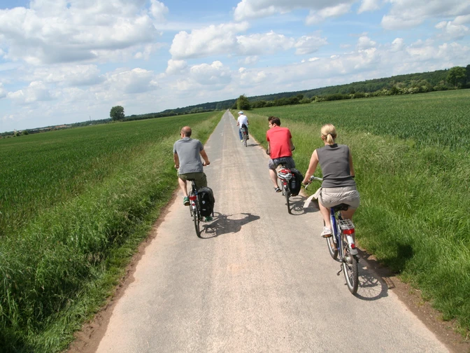 Radfahrer in Langwedel Radfahrer auf einem schmalen Weg entlang grüner Felder, blauer Himmel mit weißen Wolken oben.