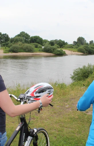 Radler an der Weser Zwei Frauen stehen mit Fahrrädern am Weserufer, blicken auf den ruhigen Fluss und die Natur.