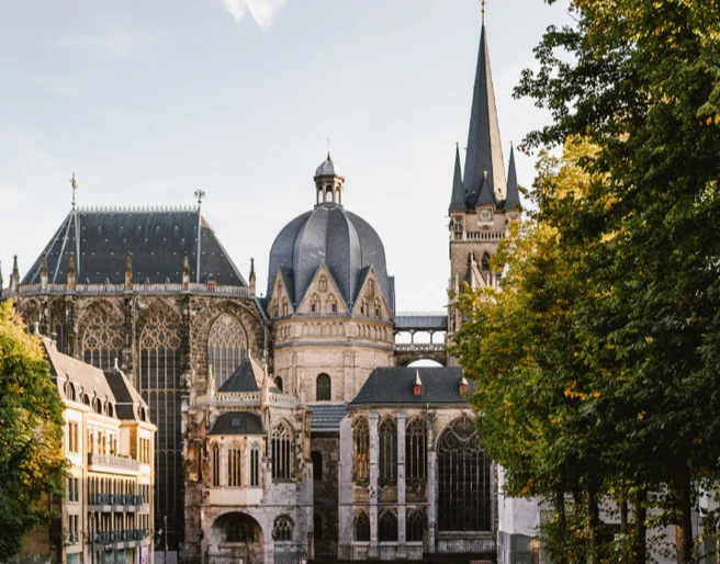 Aachener Dom vom Katschhof Blick über den Katschhof auf den Dom, rechts und links stehen grüne Bäume.