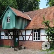 Plaggen Mühle Döhren Fachwerkhaus der Plaggen Mühle Döhren mit backsteinrotem Dach, umrahmt von dichtem Grün der Natur.