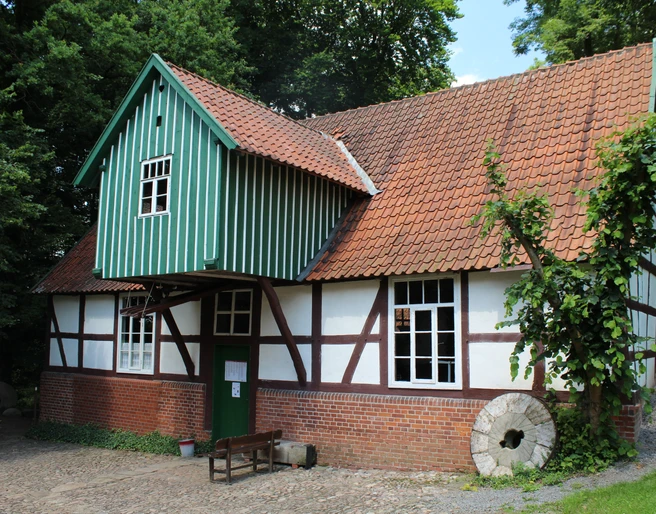 Plaggen Mühle Döhren Fachwerkhaus der Plaggen Mühle Döhren mit backsteinrotem Dach, umrahmt von dichtem Grün der Natur.
