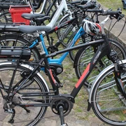 Mehrere Fahrräder stehen geordnet auf einem gepflasterten Parkplatz, bereit zur Nutzung.