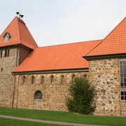 St.-Gangolf-Kirche in Wietzen Historische Backsteinkirche mit roten Ziegeldächern und markantem Kirchturm, eingebettet in grüne Wiese.