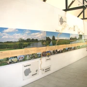 Innenansicht eines Informationszentrums mit Wandinstallationen und Panoramakarten der Region.