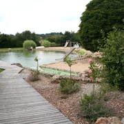 Naturfreibad Pennigsehl Naturfreibad inmitten grüner Umgebung mit Sandstrand, Rutsche und gepflegten Holzstegen.