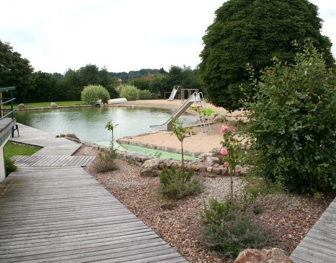 Naturfreibad Pennigsehl Naturfreibad inmitten grüner Umgebung mit Sandstrand, Rutsche und gepflegten Holzstegen.