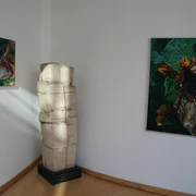 Skulptur "Knirschende Beziehung" Skulptur in einem Raum neben Leinwandbildern, dargestellt in minimalistischem Stil mit natürlichen Motiven.