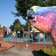 Aalskulptur Hoya Bunte Aalskulptur in Hoya, Niedersachsen, mit Maibaum und Bäumen im Hintergrund, bei klarem Himmel.