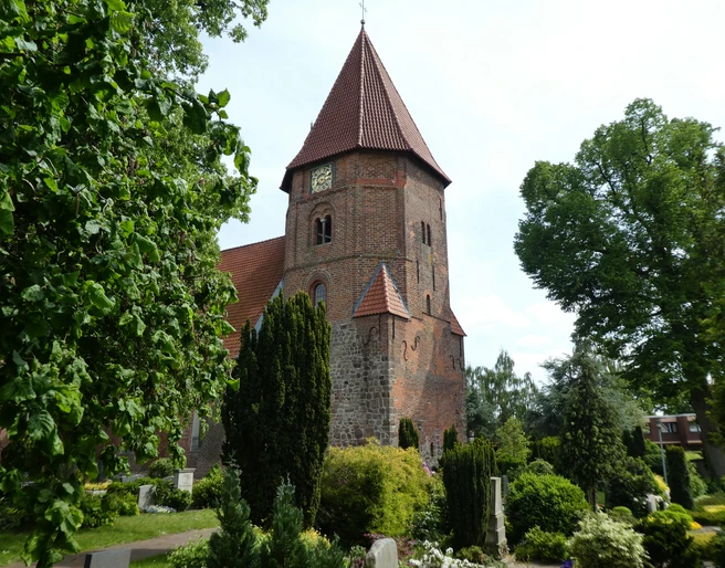 St. Laurentius-Kirche Achim Backsteinkirche mit markantem Turm und rotem Dach, umgeben von gepflegtem Grün und Baumbestand.