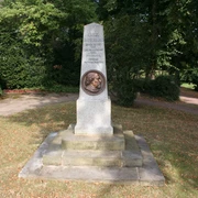 Oppermann Denkmal Ein Steinmonument mit Büste, umgeben von Bäumen in einem Park, ehrt eine historische Figur.
