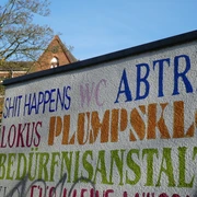 Öffentliches WC Parkplatz Rathaus Achim Bunte Schriftzüge auf einer Wand markieren ein öffentliches WC in der Nähe des Rathauses von Achim.