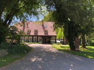 Forsthaus Heiligenberg Ein traditionelles Fachwerkhaus mit rotem Ziegeldach, eingebettet in üppigem, grünen Baumbestand.