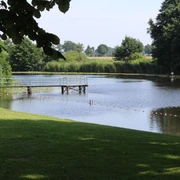 Badestelle Blender See Badestelle am Blender See mit Steg, umgeben von grüner Wiese und Bäumen, lädt zum Entspannen ein.