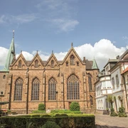 St. Lambertus Kirche in Ostercappeln Außenansicht einer gotischen Kirche mit hohen Fenstern, umliegenden Gebäuden und grünem Garten.