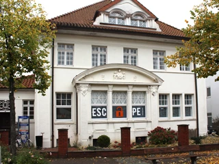 Escape Nienburg Historisches Gebäude in Nienburg, weiß gestrichen, mit Escape-Room-Logo in den Fenstern. 