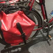 Rote Fahrradtasche aus wasserdichtem Material an einem Fahrradrahmen, geschützt vor Regen.