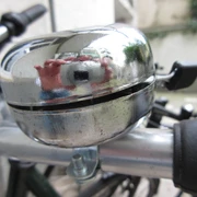 Silberne Fahrradklingel auf einem Lenker, leicht abgenutzt mit einer reflektierenden Oberfläche.