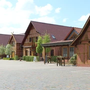 Historisches Hotelgebäude aus rotem Backstein mit Holzdetails, umgeben von einer gepflasterten Fläche.