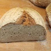 Brot Halbiertes, krustenbetontes Brot auf einem Holzbrett mit feinem Mehl bestäubt.