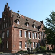 Historisches Backsteingebäude mit spitzem Giebel, hohen Fenstern und verzierten Dachgauben in Hoya.