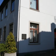 Mohrhoff-Haus Mohrhoff-Haus: Ein zweigeschossiges, weißes Gebäude mit dunklen Fenstern unter klarem Himmel.