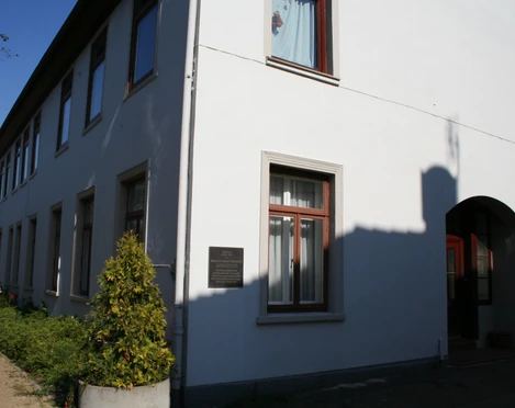 Mohrhoff-Haus Mohrhoff-Haus: Ein zweigeschossiges, weißes Gebäude mit dunklen Fenstern unter klarem Himmel.