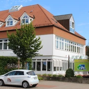 Rathaus Bruchhausen-Vilsen: Modernes Bauwerk mit spitzem Giebeldach, umgeben von grünen Bäumen.