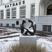 Zwei bronzene Figuren sitzen schneebedeckt auf einem Sockel vor dem historischen Rathaus Uchte.