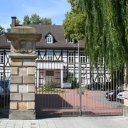 Altes Amtshaus Ein historisches Fachwerkhaus mit gepflegtem Garten, flankiert von mächtigen Steinsäulen.