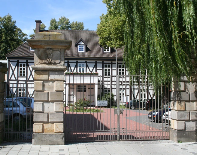 Altes Amtshaus Ein historisches Fachwerkhaus mit gepflegtem Garten, flankiert von mächtigen Steinsäulen.