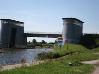 Intscheder Wehr Zwei Türme flankieren das Intscheder Wehr über einem Fluss, umgeben von grüner Vegetation.