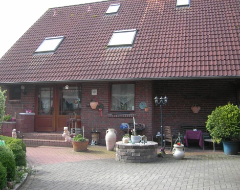 Zur Freilichtbühne Ein rotes Backsteinhaus mit Satteldach, bepflanztem Vorgarten und dekorativen Terrakottatöpfen.