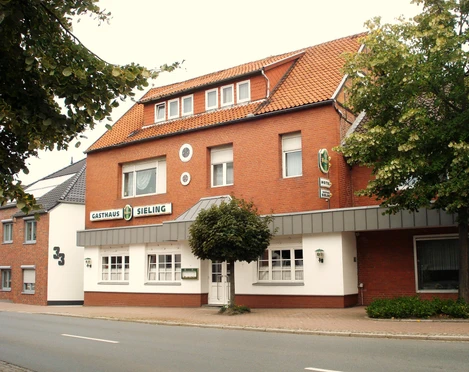 Hotel Sieling Das Hotel Sieling präsentiert eine rote Backsteinfassade mit klassischem Satteldach und grüner Beschilderung.