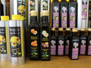 Essig und Öl Verschiedene Flaschen mit hochwertigen Essigen und Ölen auf einem Holzregal, bunt etikettiert.