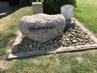 Aussichtspunkt Haarberg Ein großer Felsblock mit der Aufschrift "Windkraft" liegt auf einem mit Steinen umrandeten Platz.