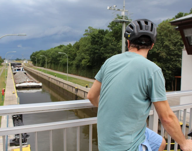 Schleuse Schlüsselburg Ein Radfahrer beobachtet von einer Brücke aus ein vorbeifahrendes Schiff in der Schleuse Schlüsselburg.