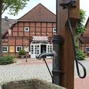 Ortsmitte Bruchhausen-Vilsen Historisches Fachwerkhaus mit Café im Zentrum von Bruchhausen-Vilsen und alter Wasserpumpe im Vordergrund.