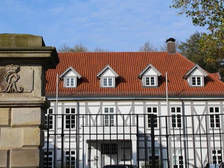 Altes Amtshaus Fachwerkhaus mit rotem Ziegeldach und markantem Giebeldach, hinter schmiedeeisernem Zaun.
