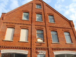 Biskuithaus Historisches Backsteingebäude mit großen Fenstern und dekorativen Ziegelmustern unter blauem Himmel.