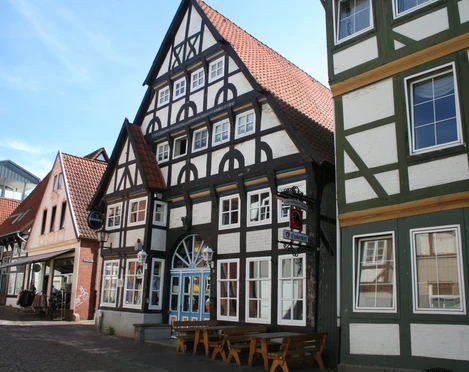 Bürgerhaus Fachwerkgebäude mit roten Ziegeldächern, typisch norddeutscher Stil, Straßenszene im Sonnenschein.