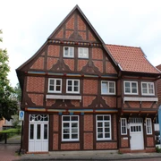 Das Thießensche Haus Fachwerkhaus mit markanten roten Ziegelflächen, angereichert durch weiße Fenster, in einem städtischen Umfeld.