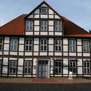 Hakenhof Zweistöckiges Fachwerkhaus mit roten Ziegeldach und symmetrisch angeordneten weißen Fensterreihen.