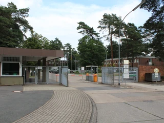 Kaserne Langendamm Eingang der Kaserne Langendamm, gesäumt von Kiefern und Backsteingebäuden, mit Schranken und Schildern.