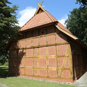 Rövers Schafstall Ein traditionelles Fachwerkgebäude mit rotem Ziegeldach im Grünen bei sonnigem Wetter.