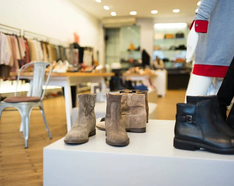 PREGO Das Bild zeigt moderne Schuhe und Stiefel in einer stilvollen Boutique auf hölzernem Boden präsentiert.The picture shows modern shoes and boots presented in a stylish boutique on a wooden floor.