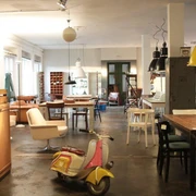 Geliebte Möbel Ein gemütlicher Vintage-Möbelladen mit buntem Roller, stilvollen Leuchten und Holzmöbeln.A cozy vintage furniture store with colorful scooters, stylish lamps and wooden furniture.